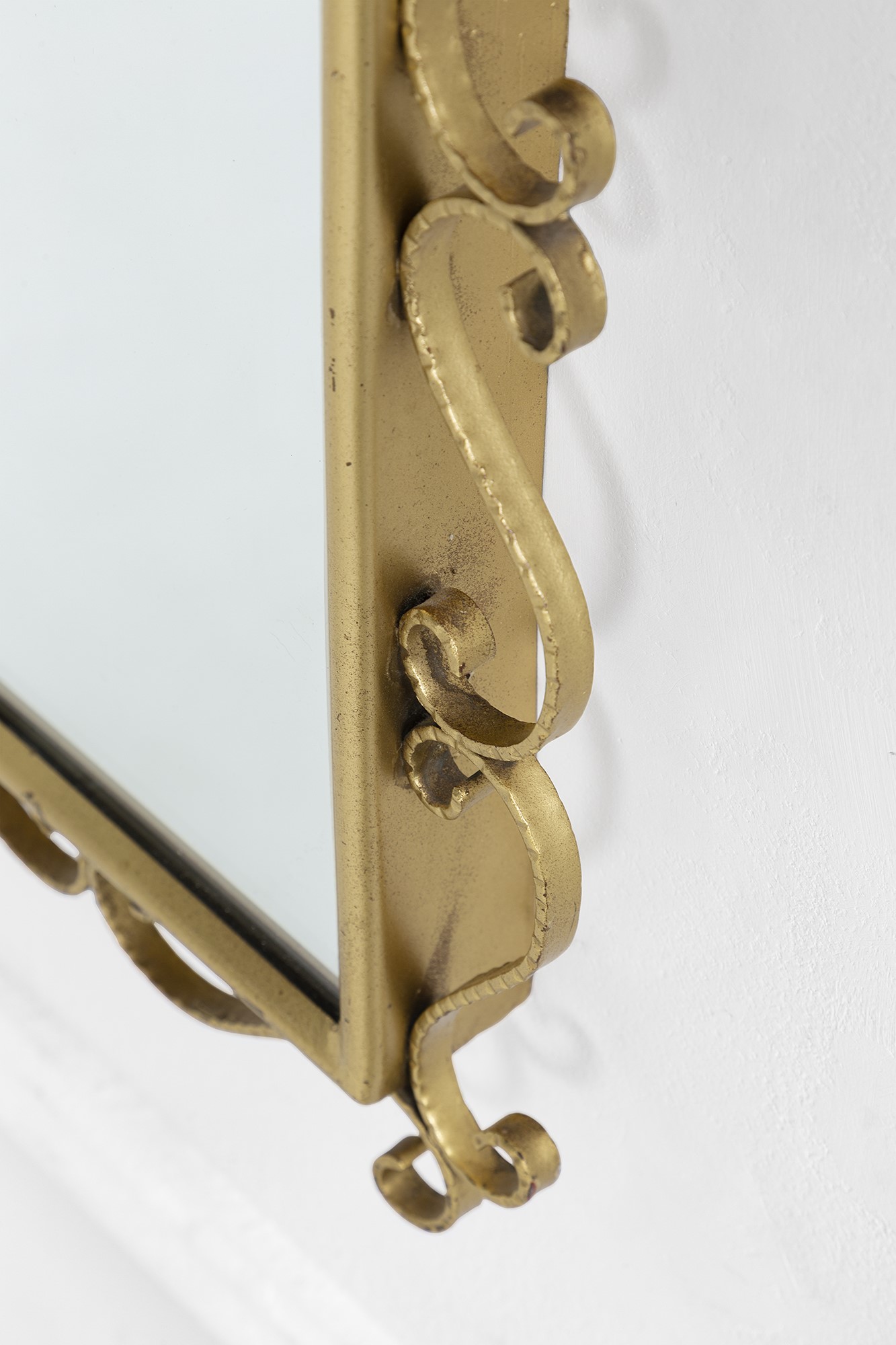 Specchiera in metallo dorato sagomato a volute con vetro specchiato, circa metà XX secolo
